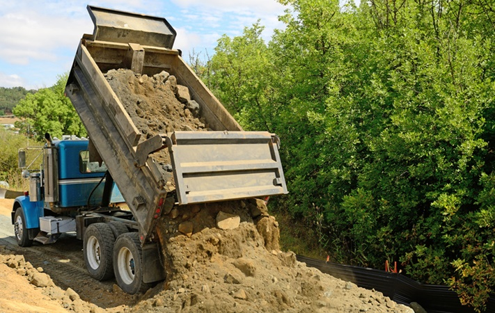 Dump truck unloading sand and gravel at construction site